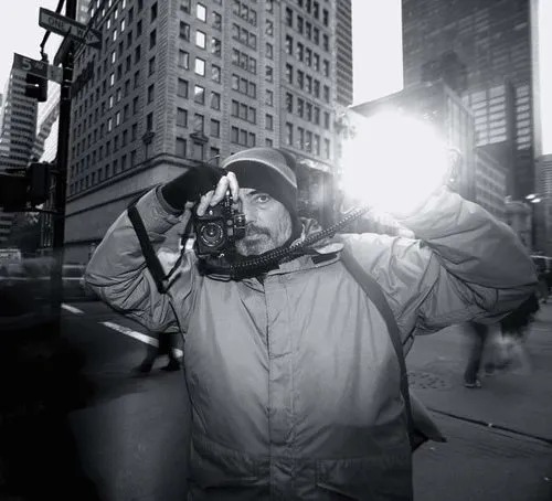 Bruce Gilden photographiant dans une rue de New York, flash à la main