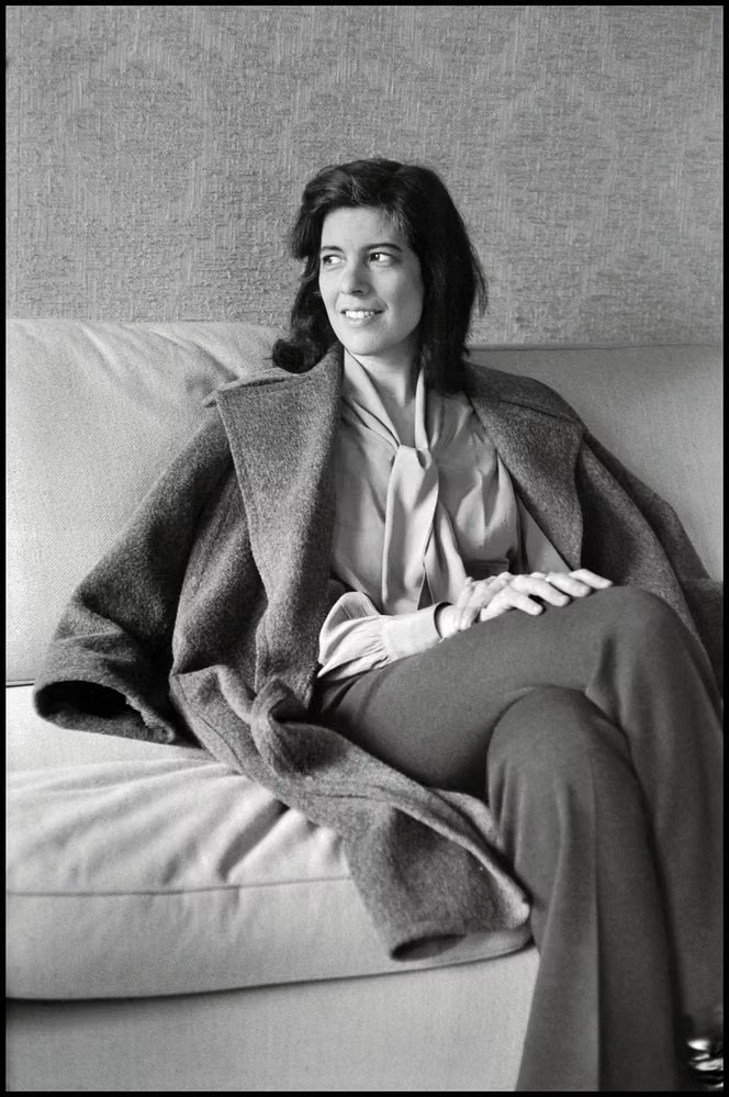 Susan Sontag assise sur un canapé, un manteau sur les épaules